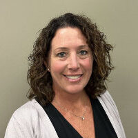 Smiling woman with curly hair in a casual office.