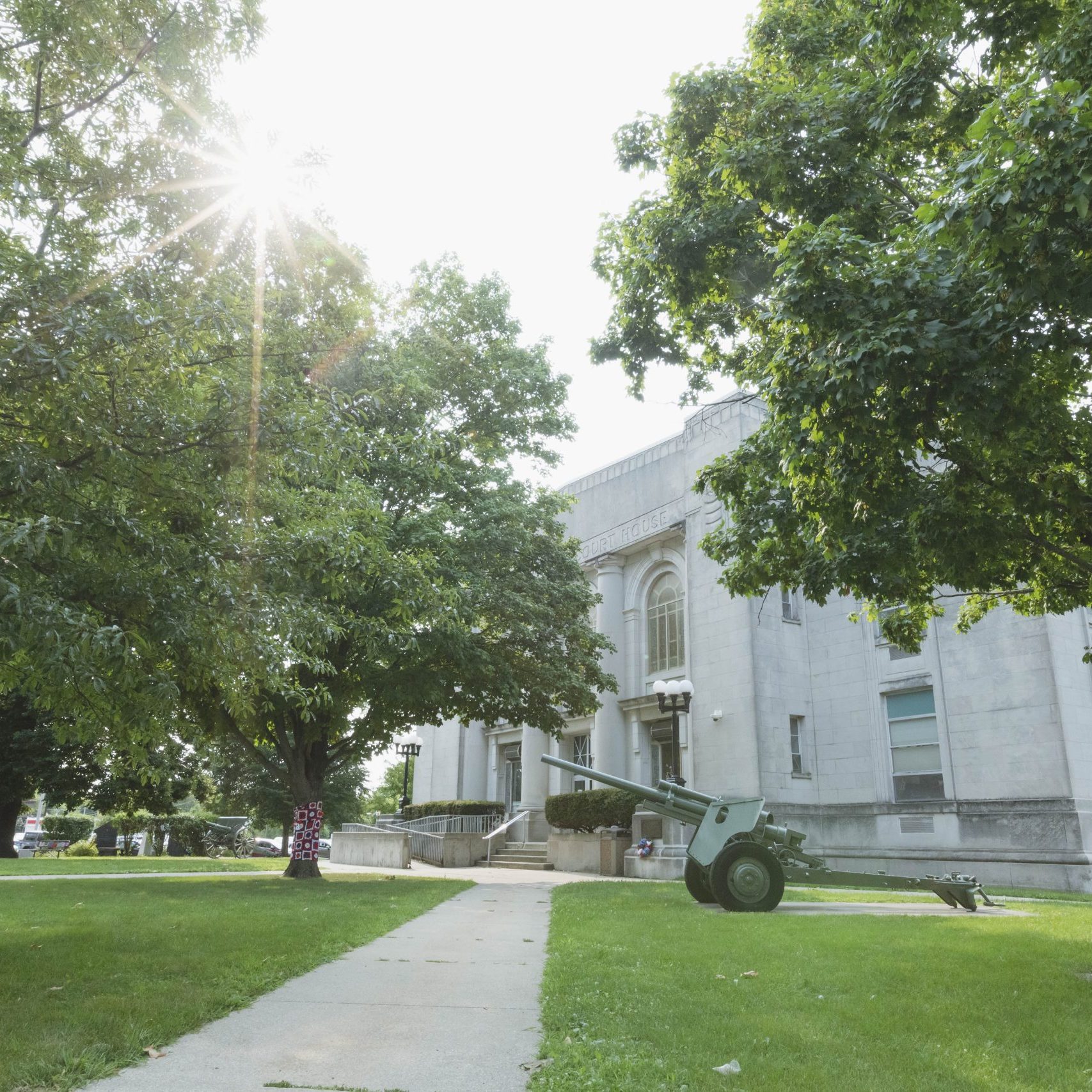 Sunny day at historic courthouse with green trees.